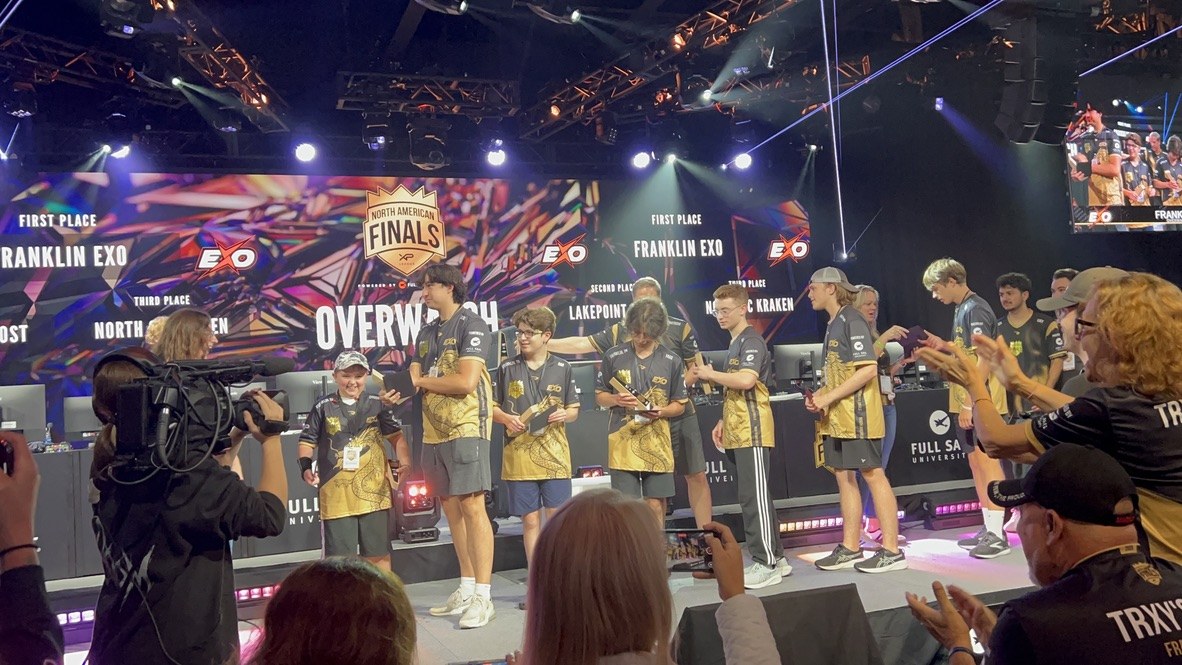 Wide award-stage photo showing the STORM team, crowd and event production